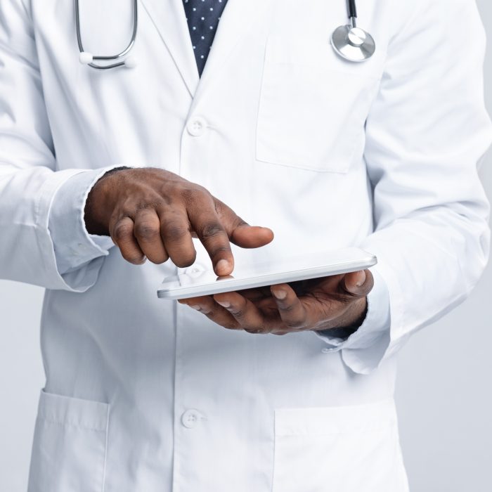 Cropped of african male doctor using digital tablet over white